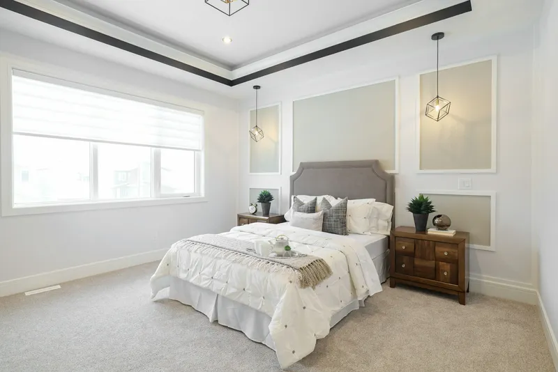 Chambre avec plafond à caisson, moulures murales, tête de lit capitonnée grise, chevets en bois, suspensions cage et moquette grise