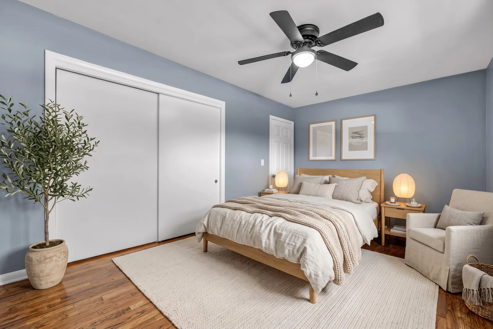 La même chambre meublée en style Nordic Light avec lit en chêne, linge blanc, lampes en papier, olivier et tapis en laine crème